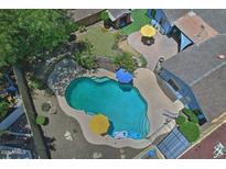 Aerial view of sparkling backyard pool with colorful umbrellas and patio furniture, great for relaxation and entertaining at 927 N Somerset Cir, Mesa, AZ 85205