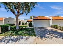 Charming single-story home with a well-manicured lawn, mature shade tree, and a two-car garage with a red tile roof at 9322 E Jenan Dr, Scottsdale, AZ 85260