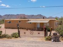 Tan single-story home with a metal gate and desert landscaping in a rural Arizona setting at 270 S Ralston Rd, Maricopa, AZ 85139