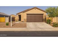Tan single-story home featuring a brown two-car garage door and low maintenance desert landscaping at 36987 N Sidewinder Dr, San Tan Valley, AZ 85140