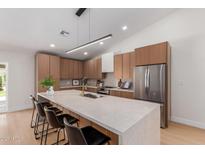 Modern kitchen featuring a large island with seating, stainless steel appliances, and wood cabinetry at 4532 E Sandra Ter, Phoenix, AZ 85032