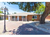 Charming brick home with a welcoming front porch and lovely landscaping with a large tree providing shade at 724 W Missouri Ave, Phoenix, AZ 85013