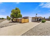 Well-maintained single-story home with a covered carport and mature tree in a xeriscaped front yard at 7711 E Farmdale Ave, Mesa, AZ 85208
