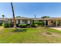 Charming single-story home featuring a lush green lawn, mature trees, and a convenient carport at 1209 W Colter St, Phoenix, AZ 85013