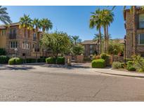 Inviting stone condominium building with lush green landscaping and palm trees in a gated community at 2470 E Roma Ave, Phoenix, AZ 85016