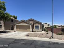 Attractive single-story home with a well-kept lawn, desert landscaping, and a two-car garage at 13004 W Saint Moritz Ln, El Mirage, AZ 85335