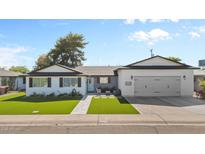 Charming single-story home with well-manicured lawn, an attached garage, and a cozy seating area by the front door at 2316 N 81St St, Scottsdale, AZ 85257