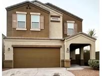 Charming two-story home featuring a brown stucco exterior, attached two-car garage, and a covered entryway at 29906 W Whitton Ave, Buckeye, AZ 85396