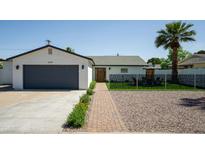 Charming single-story home featuring a landscaped front yard, brick walkway, and a spacious two-car garage at 6907 E Palm Ln, Scottsdale, AZ 85257