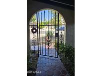 Wrought iron gate leads to front porch with red tile, and decorative wreath adorns the entryway at 1743 W Acoma Dr, Phoenix, AZ 85023