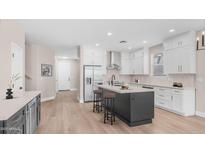 Bright kitchen features white cabinets, stainless steel appliances, light backsplash, and an island with seating at 22706 N 17Th St, Phoenix, AZ 85024