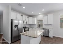 Kitchen features stainless steel appliances, granite countertops, and white cabinetry, offering a blend of style and functionality at 41041 W Somers Dr, Maricopa, AZ 85138