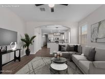 Bright living room with modern decor including gray sectional, side table, and archway to kitchen, creating inviting space at 41041 W Somers Dr, Maricopa, AZ 85138
