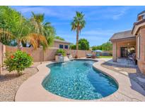Sparkling pool features rock waterfall, lush landscaping, and ample seating for relaxing in the sun at 1144 E Nunneley Rd, Gilbert, AZ 85296