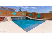 Refreshing pool with a unique tile design, surrounded by a decorative wall and steps leading to a serene waterfall feature at 25840 W Whyman St, Buckeye, AZ 85326