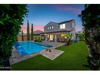Beautiful backyard featuring a refreshing pool, lush lawn, covered patio, and palm trees, perfect for outdoor living at 7939 W Fetlock Trl, Peoria, AZ 85383