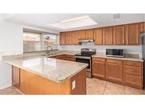 An updated kitchen with granite countertops, wood cabinets and stainless steel appliances provides ample counter space at 8807 W Cinnabar Ave, Peoria, AZ 85345