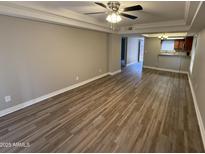 Open-concept living room featuring wood floors, tray ceiling with ceiling fan, and natural light at 3434 W Danbury Dr # A206, Phoenix, AZ 85053