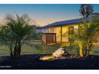 Charming home exterior featuring a manicured lawn, palm trees, and illuminated landscaping rocks at 1818 W Highland Ave, Phoenix, AZ 85015