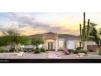 Home exterior features desert landscaping and a covered entry with landscape lighting providing a serene and inviting ambiance at 3946 N Pinnacle Hills Cir, Mesa, AZ 85207