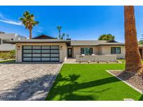 Charming home exterior with a modern design, desert landscaping, and an impressive garage door at 8119 E San Miguel Ave, Scottsdale, AZ 85250