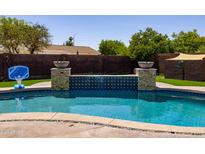 A pristine pool features a serene waterfall and a basketball hoop, offering a refreshing outdoor oasis at 1551 E Glencove St, Mesa, AZ 85203