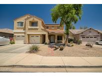Inviting two-story home featuring a three-car garage, desert landscaping, and a red tile roof on a sunny day at 17766 W Caribbean Ln, Surprise, AZ 85388