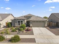 Single-story home featuring a well-manicured front yard, neutral color palette, and a two-car garage at 18865 W Mescal St, Surprise, AZ 85388
