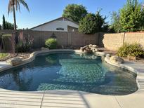Inviting backyard pool with rock waterfall feature, perfect for relaxation and outdoor enjoyment at 2092 E Smoke Tree Rd, Gilbert, AZ 85296