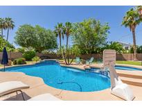 Beautiful backyard with a sparkling blue pool, lush greenery, and comfortable lounge chairs at 2438 S Chestnut Pl, Chandler, AZ 85286