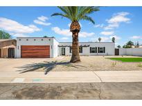 Charming single-story home with a modern design and a well-maintained yard and a wood garage door at 2801 E Sunnyside Dr, Phoenix, AZ 85028