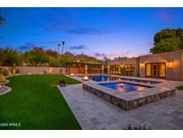 Inviting backyard featuring a pool, spa, lush lawn, and outdoor kitchen with bar, great for entertaining at 4518 E Solano Dr, Phoenix, AZ 85018