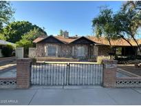 Charming stone facade home with a brick and wrought iron fence under a clear blue sky at 344 E Aepli Dr, Tempe, AZ 85282
