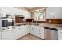 Updated kitchen features white cabinetry, stainless steel appliances, tile backsplash, and granite countertops at 10621 W Oakmont Dr, Sun City, AZ 85351