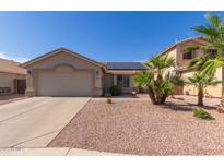 Charming single-story home featuring desert landscaping, solar panels, and an attached two-car garage at 16554 W Saguaro Ln, Surprise, AZ 85388