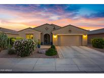Charming single-story home featuring a two-car garage and desert landscaping beneath a vibrant sunset sky at 20194 N Riverbank Rd, Maricopa, AZ 85138