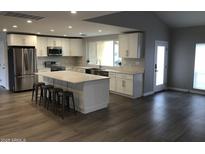 Bright kitchen features white cabinets, stainless steel appliances, large island with seating, and hardwood floors at 4910 E Charter Oak Rd, Scottsdale, AZ 85254