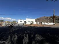 Modern, white home featuring a minimalist design and desert landscaping, complemented by a mountain backdrop at 9027 S 19Th St, Phoenix, AZ 85042