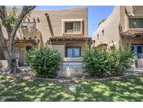 Charming townhome with well-manicured lawn, mature trees, and welcoming sign with light blue door and window trim at 1446 E Grovers Ave # 13, Phoenix, AZ 85022