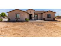 Charming single-story home with tan stucco exterior and a low-pitched roof, front yard is not yet landscaped at 20310 W Hubbard Rd, Buckeye, AZ 85326