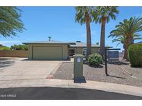 Charming single-story home featuring a two-car garage, palm trees, and a manicured front yard at 26649 S Howard Dr, Sun Lakes, AZ 85248