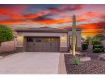 Beautiful home with a two-car garage, desert landscaping, and a dramatic sunset sky at 28878 N 127Th Ln, Peoria, AZ 85383