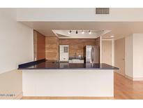 Modern kitchen features an island with blue countertops, stainless steel refrigerator, and stylish lighting at 4750 N Central Ave # N7, Phoenix, AZ 85012