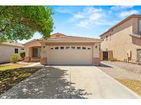 Inviting single-story home with a two-car garage, set against a blue sky and mature tree at 817 E Lamonte St, San Tan Valley, AZ 85140