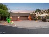 Desert home exterior with a wide driveway, two-car garage, desert landscaping and exterior lighting at 11299 E Greythorn Dr, Scottsdale, AZ 85262