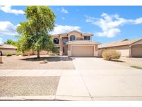 Tan two-story home with a desert landscape, a large shade tree, and a two car garage at 2605 W Darrel Rd, Phoenix, AZ 85041