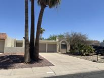 Beige stucco home featuring a two-car garage, palm trees, desert landscaping, and a concrete driveway at 632 W Fordham Dr, Tempe, AZ 85283