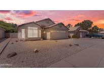 Charming single-story home featuring a two-car garage, desert landscaping, and a picturesque sunset sky at 1405 E Chicago Cir, Chandler, AZ 85225