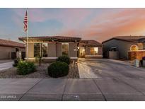 Charming single-story home featuring a tiled roof, landscaped front yard, and an American flag on a pole at 16077 W Anasazi St, Goodyear, AZ 85338