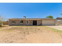 Single-story home with solar panels, light-colored siding and desert landscaping at 1676 W Sequoia Dr, Phoenix, AZ 85027